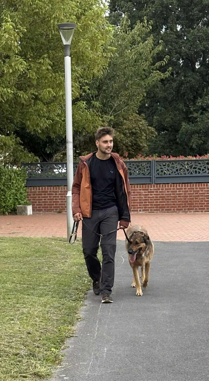 Un éducateur canin accompagne un chien en promenade éducative dans un parc urbain. Cette image illustre le travail de marche en laisse, l’apprentissage de l’obéissance et la relation de confiance entre le maître et son chien.